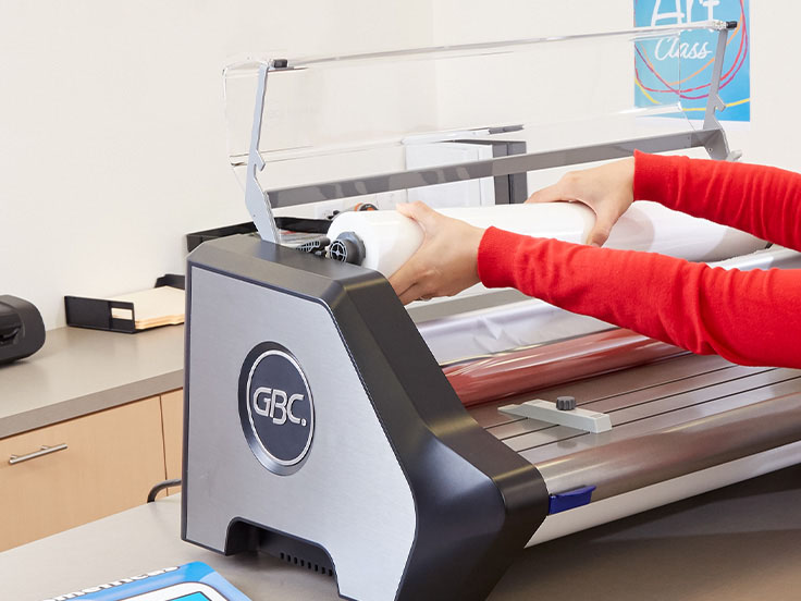 Woman loading film into GBC Catena 65 laminator